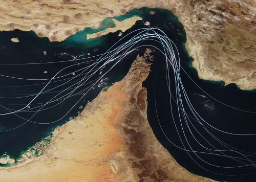 Satellite view of the Strait of Hormuz with white graphic lines representing global shipping lanes and maritime traffic between the Persian Gulf and Gulf of Oman. Strategic oil transport concept