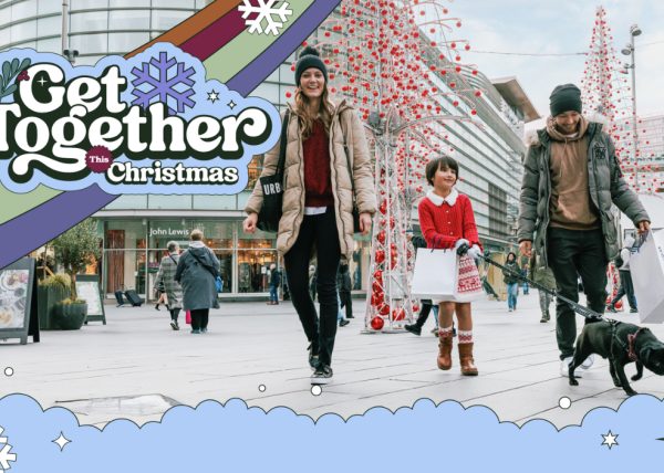A family of three walking through a shopping district with Christmas decorations up.