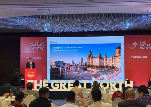 a person giving a presentation infront of a crowd. there is a large screen in the background.
